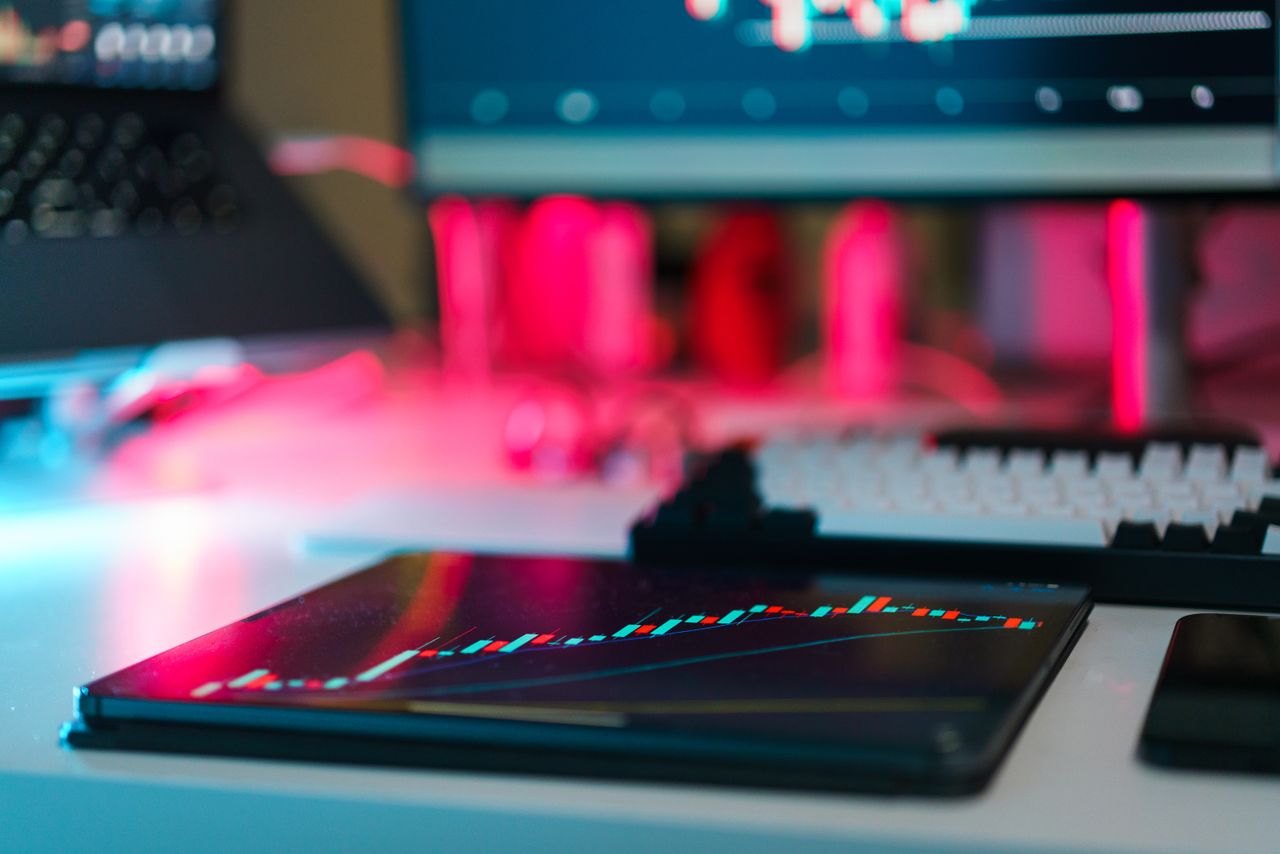 Installation de trading high-tech avec des graphiques sur une tablette et des écrans d’ordinateur, illustrant l’analyse de données et les tendances financières.